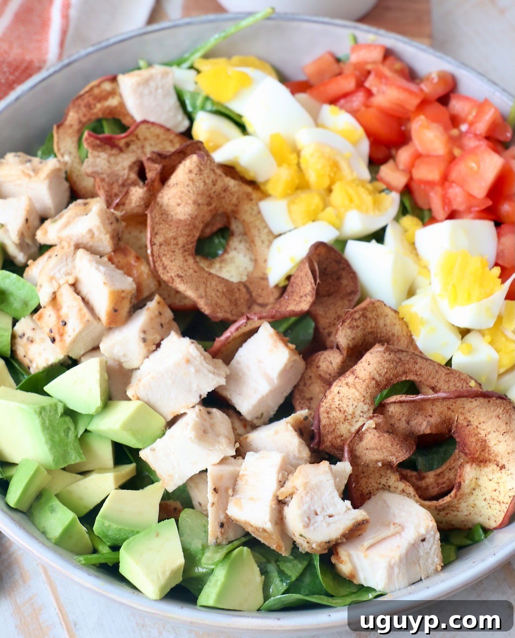 A close-up of a vibrant Cobb Salad in a bowl, showing the intricate layering and fresh textures of all ingredients. The salad appears fresh, colorful, and highly appealing, emphasizing the wholesome nature of the meal.