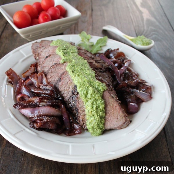 Tri Tip with Arugula Blue Cheese Pesto - A close-up of a serving of grilled tri-tip steak, topped with rich arugula blue cheese pesto.