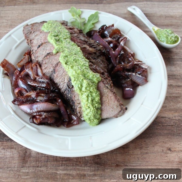 Tri Tip with Arugula Blue Cheese Pesto - A beautifully plated dish of grilled tri-tip steak with pesto and caramelized onions.
