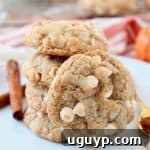 Pumpkin spice white chocolate chip cookies stacked up on a plate