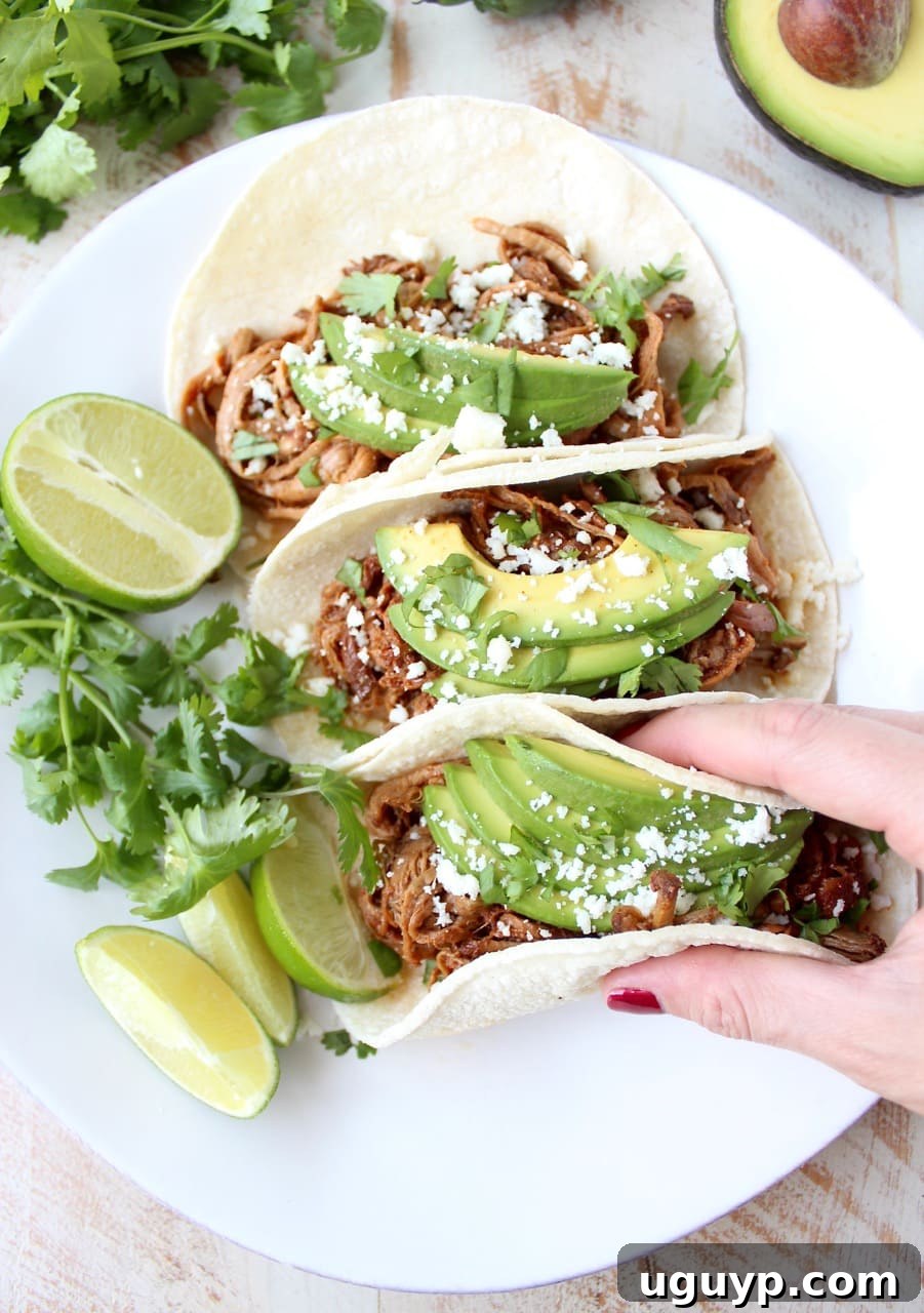 Delicious Slow Cooker Pulled Pork Tenderloin Chipotle Honey Tacos garnished with fresh cilantro and lime wedges, perfect for an easy weeknight meal or game day.