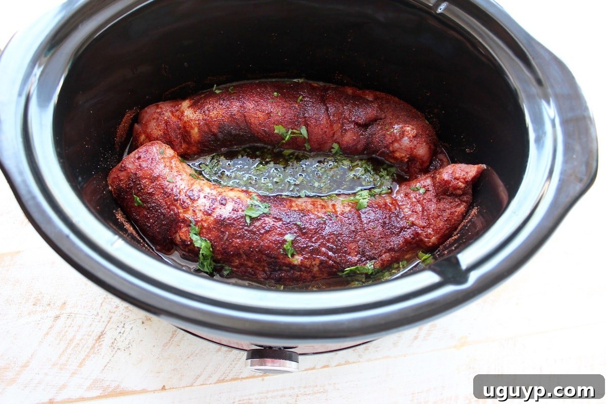 Honey-lime-cilantro marinade being poured over the seasoned pork tenderloin in a slow cooker.