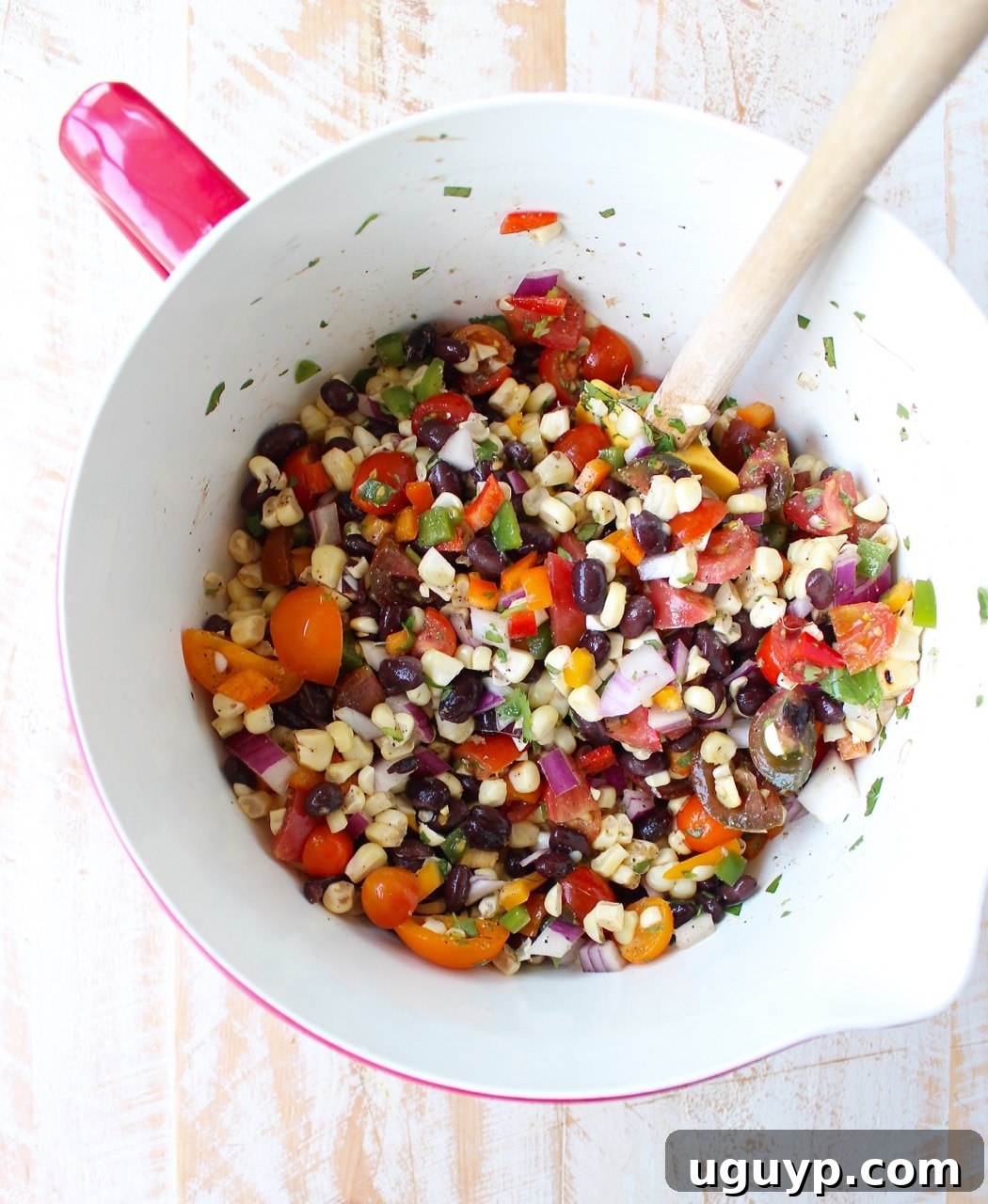 A large mixing bowl filled with vibrant black bean corn relish, ready to be seasoned.