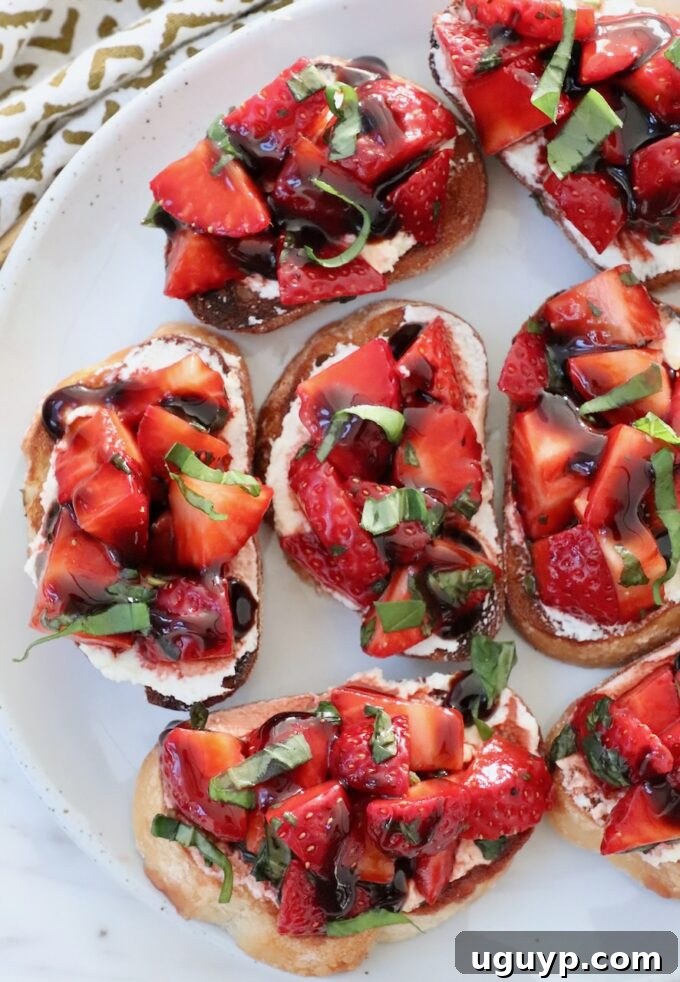 A perfectly assembled strawberry bruschetta, featuring the vibrant strawberry topping on a bed of creamy goat cheese, served on a toasted baguette slice.