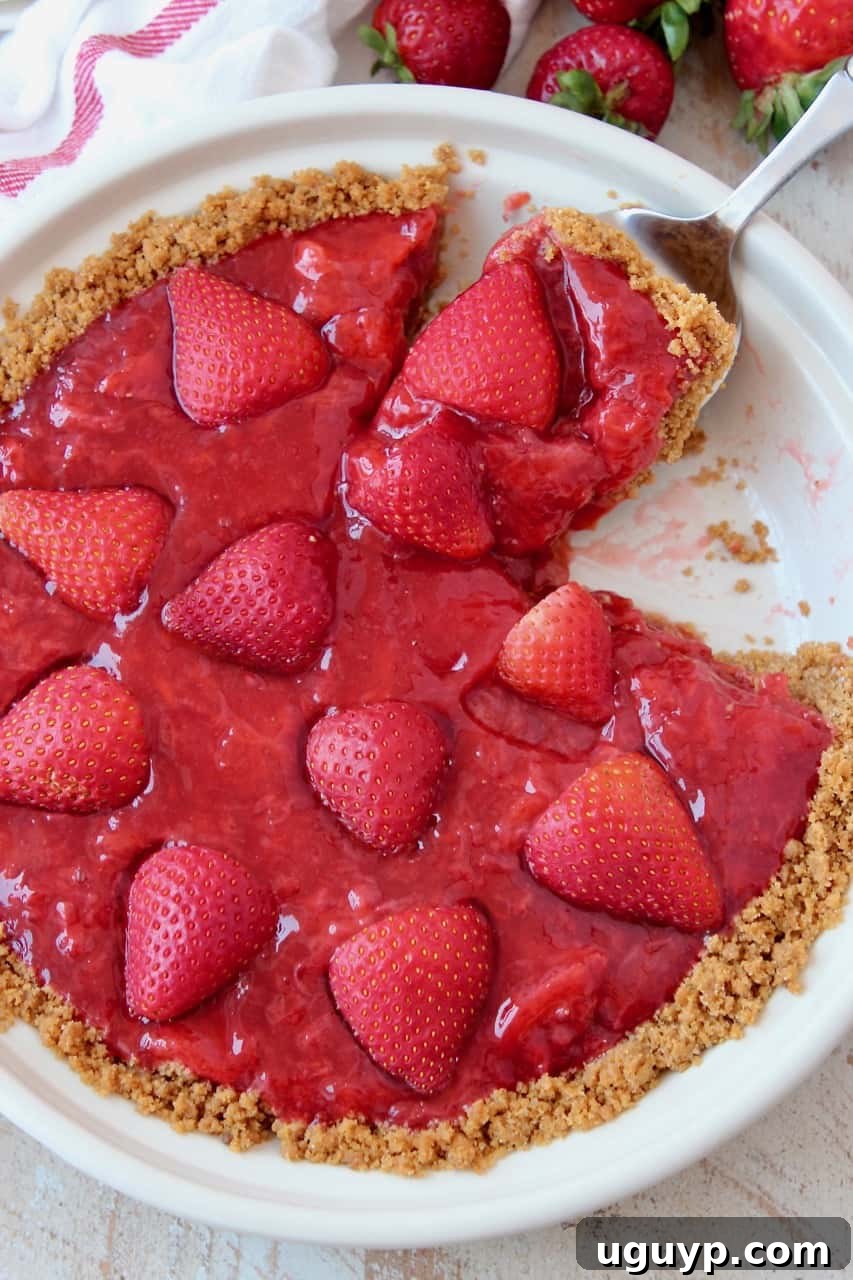 A slice of fresh strawberry pie being carefully lifted out of the whole pie, showing the perfect texture of the filling and crust.