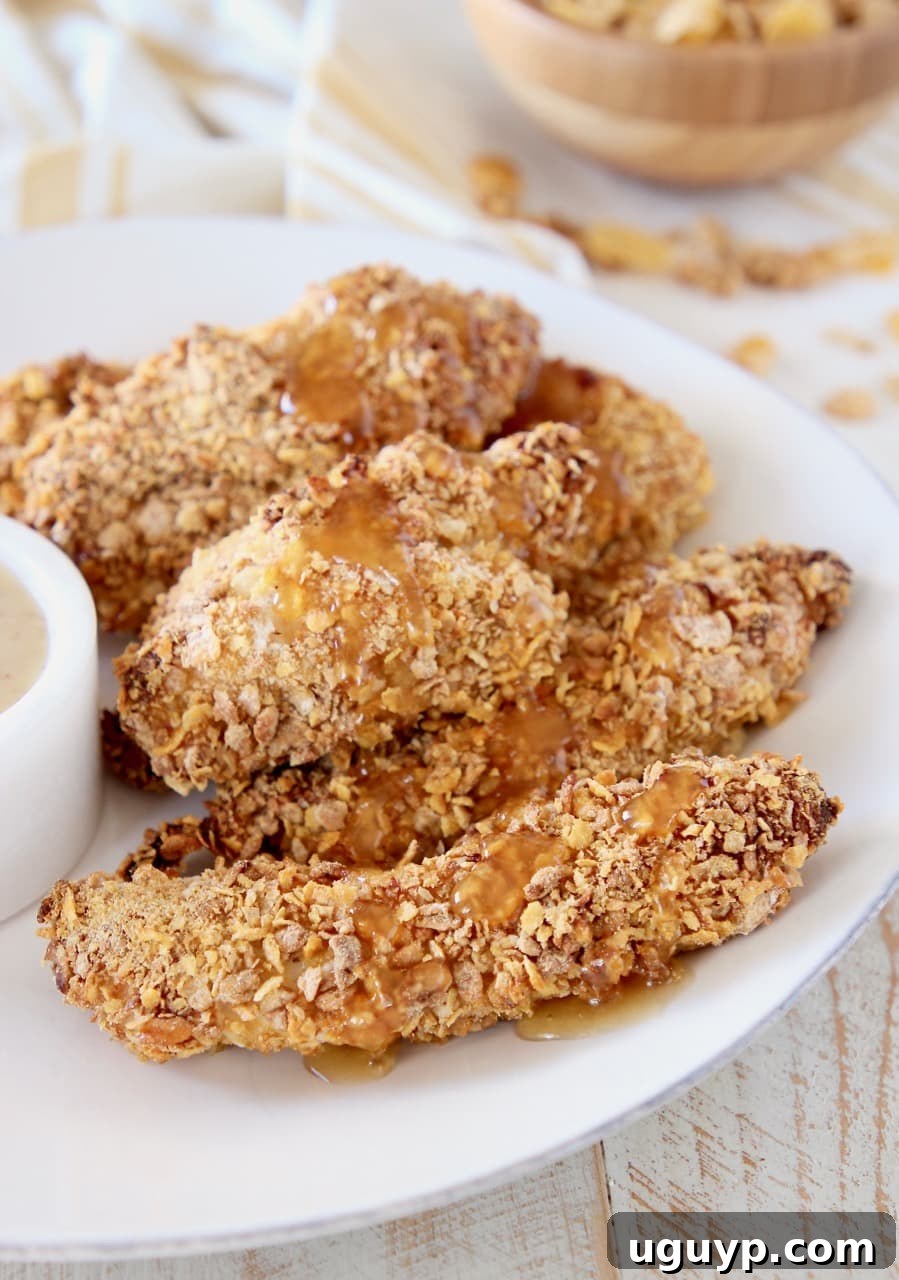 Honey Bunches of Oats chicken strips on plate drizzled with honey with bowl of cereal in the background