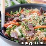 beef stir fry with noodles in skillet with spoon
