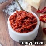 Sun dried tomato pesto in small white bowl on wood cutting board