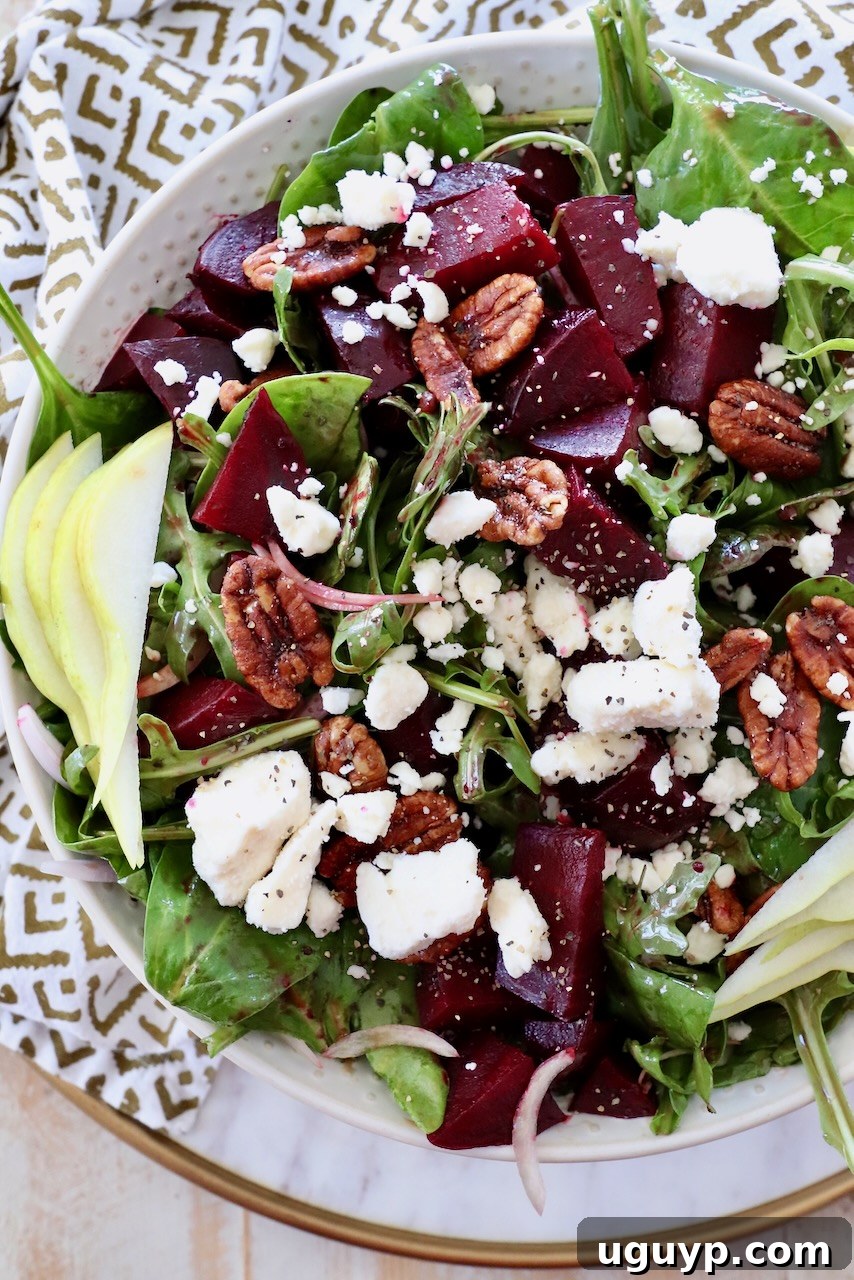 A beautifully presented beet salad in a serving bowl, garnished with crumbled feta cheese and fresh pear slices.
