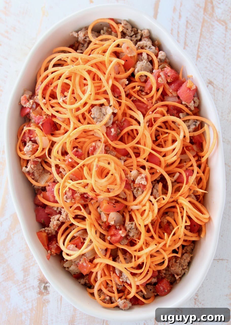 Sweet potato noodles, ground turkey and tomatoes in an oval baking dish