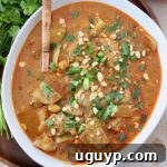 cooked chicken thighs and vegetables in curry sauce in bowl with serving spoon