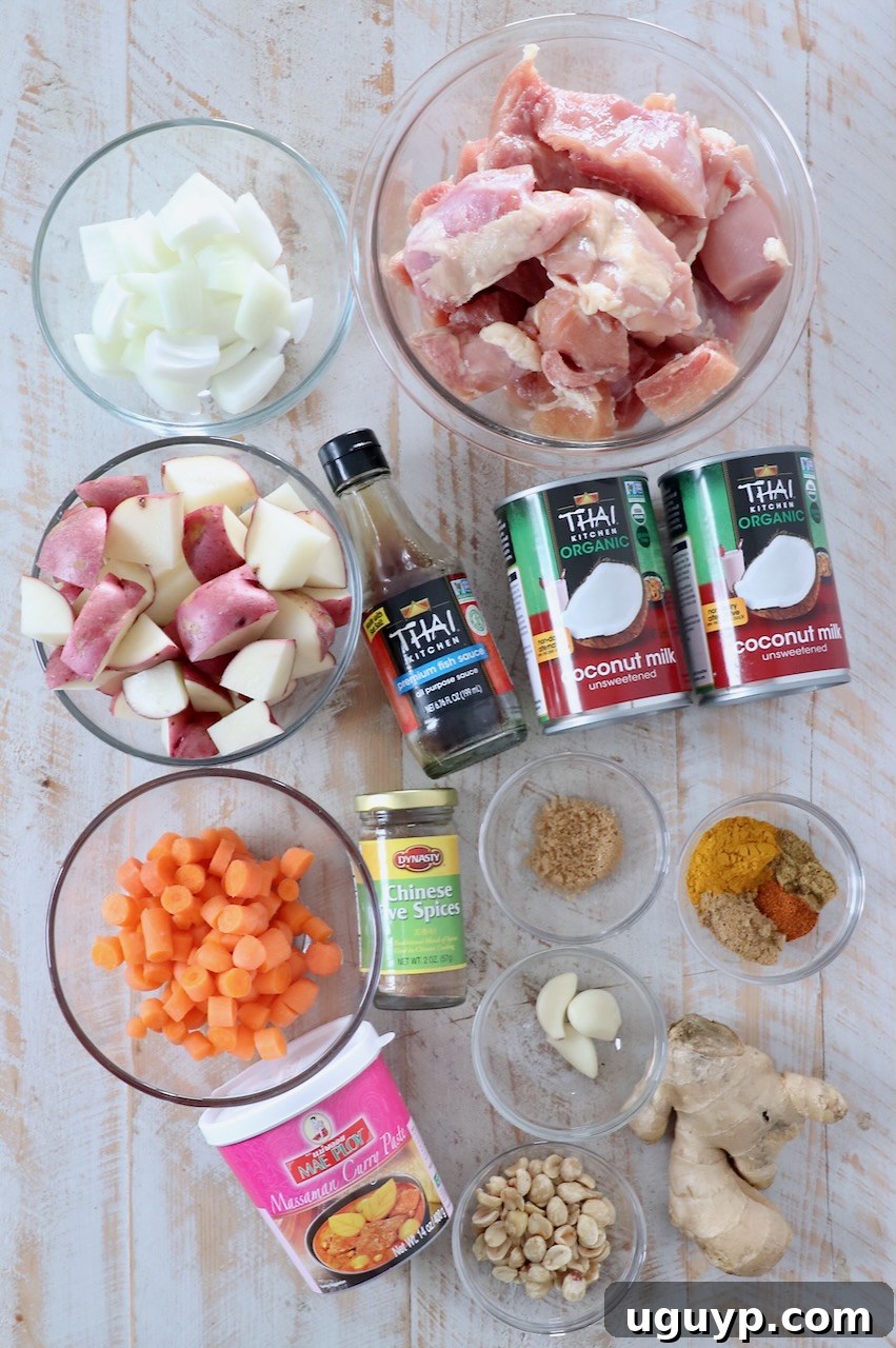 Assortment of fresh ingredients for Massaman Curry Chicken laid out on a white wooden board.