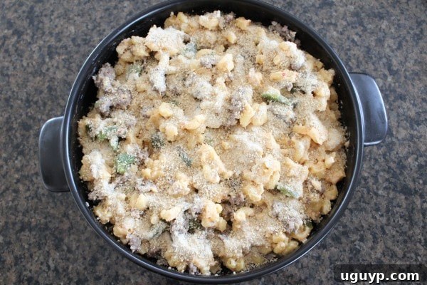 Sausage Jalapeño Macaroni and Cheese topped with breadcrumbs, ready to be baked in an oven-safe skillet or baking dish.