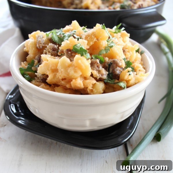A close-up of a fork scooping a bite of Sausage Jalapeño Macaroni and Cheese, highlighting the melted cheese, pasta, sausage, and roasted jalapeño pieces.