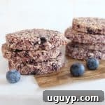 Close-up of a homemade oatmeal berry granola bar with visible oats, almonds, and dried berries.