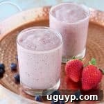 Fruit smoothie in glasses on copper tray with strawberries and blueberries