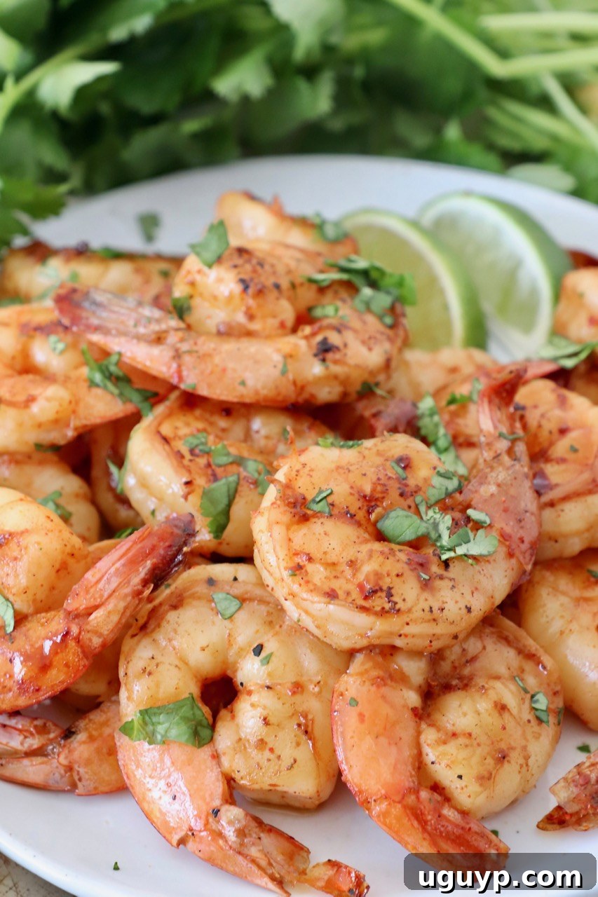 Grilled shrimp served on a white plate with fresh lime wedges