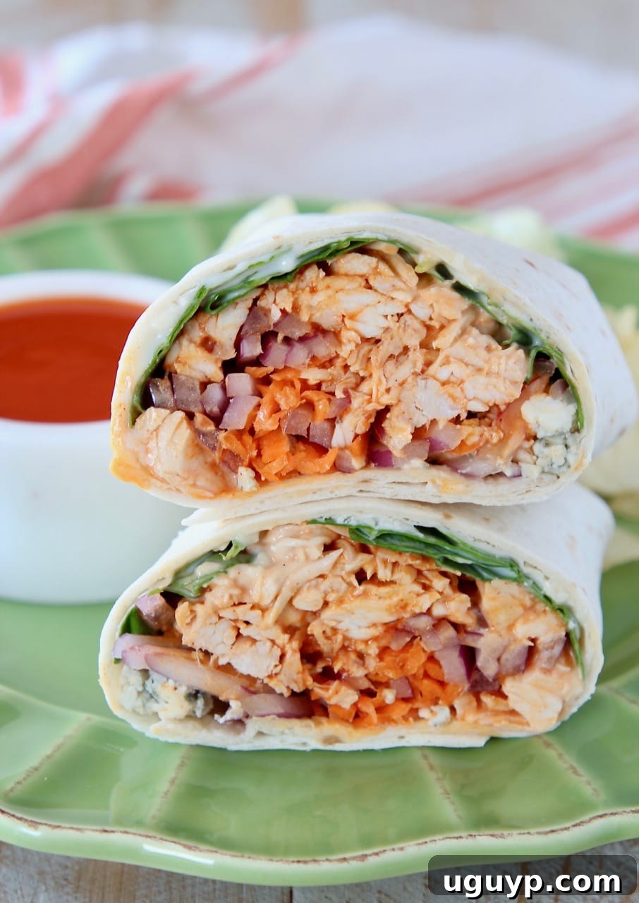 A vibrant buffalo chicken wrap, expertly sliced in half and stacked on a green plate, ready to be enjoyed.