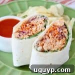 A close-up of a buffalo chicken wrap, sliced in half and stood upright, invitingly presented on a green plate, ready to be savored.