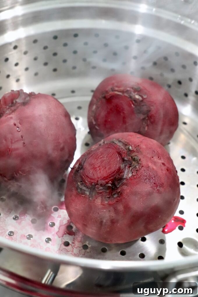 Steamed beets, vibrant and tender, resting in a steamer basket after cooking.