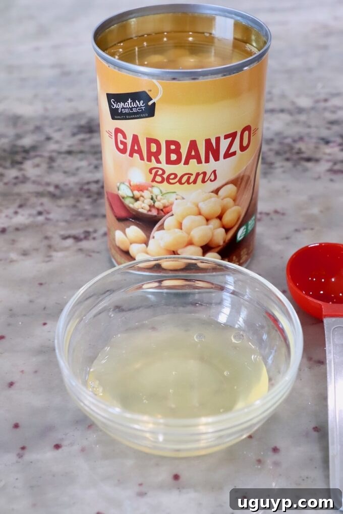 Aquafaba, the liquid from canned garbanzo beans, collected in a small glass bowl.