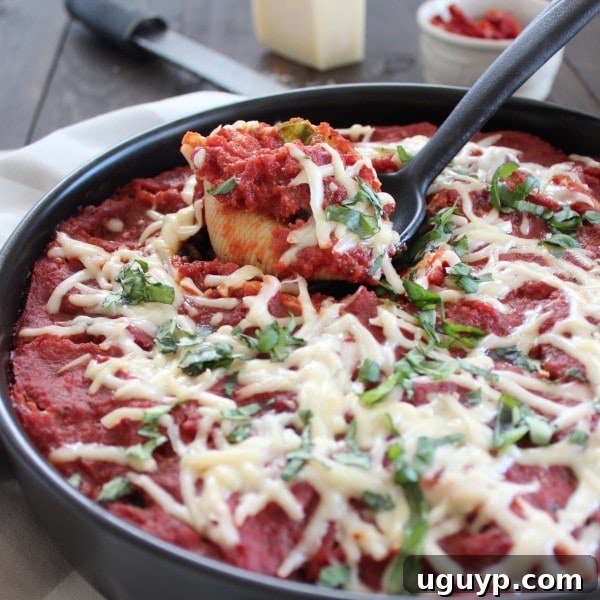 A black spoon scooping out a stuffed shell from a pot, showcasing the rich filling and sauce.