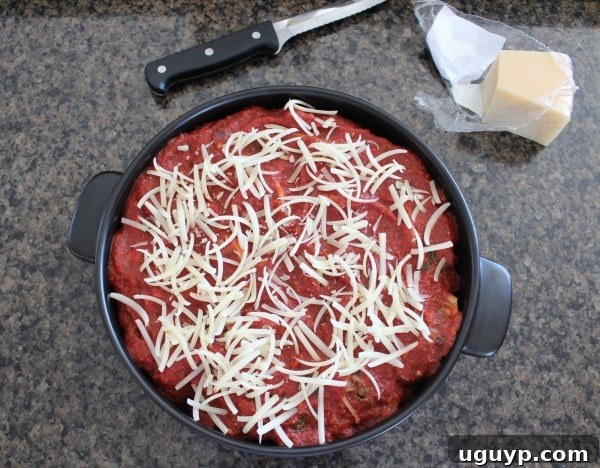 An oven-safe pot filled with stuffed shells, lavishly covered with red sauce and a golden layer of Parmesan cheese.