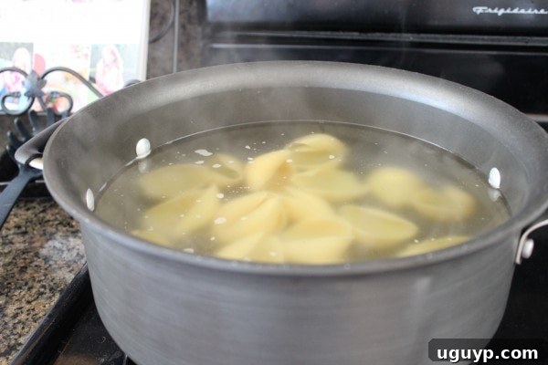 A pot filled with boiling water and pasta shells, cooking to al dente.