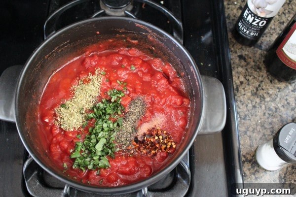 Rich Red Wine Tomato Sauce simmering in a pot on the stovetop.