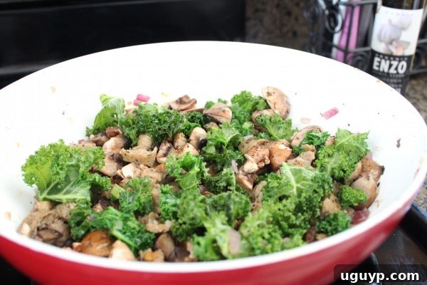 A skillet filled with browned sausage, sautéed kale, and onions, ready for the filling.
