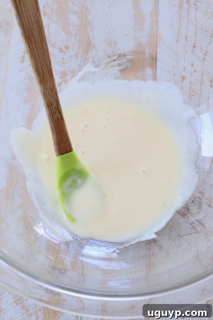 Mayonnaise and honey being combined in a bowl with a spatula to create the creamy sauce.