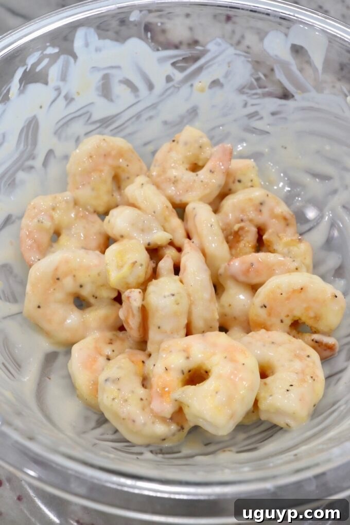 Cooked, crispy shrimp being tossed in the creamy honey sauce until fully coated.