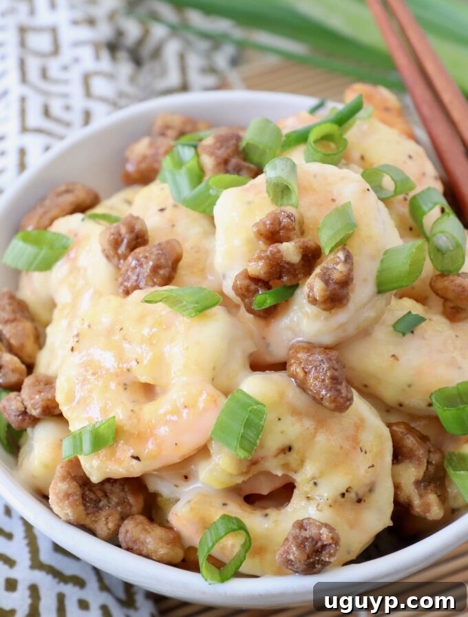 A serving bowl filled with delicious Honey Walnut Shrimp, garnished with diced green onions.