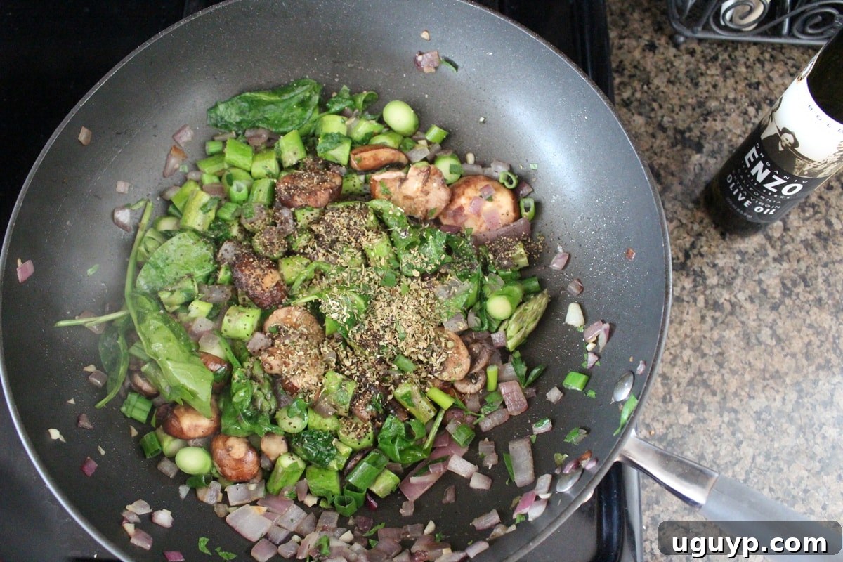 Fresh and dried herbs being added to the sautéed vegetables in a skillet for the spring vegetable stuffing
