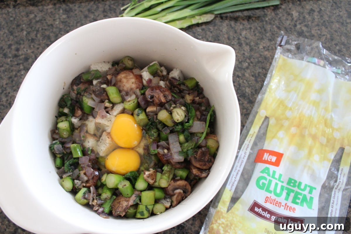 Eggs and vegetable broth being poured over the bread and vegetable mixture in a bowl, to bind the stuffing