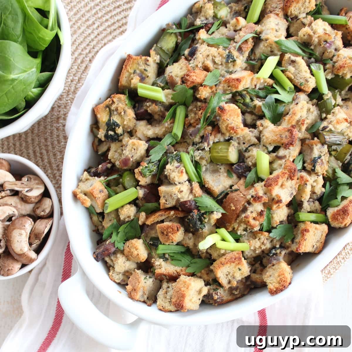 The finished Gluten Free Spring Vegetable Stuffing, golden brown and garnished with fresh herbs, in a baking dish