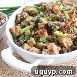 A close-up of the finished Gluten Free Spring Stuffing, showing a golden crispy top and a moist, flavorful interior, garnished with fresh herbs.