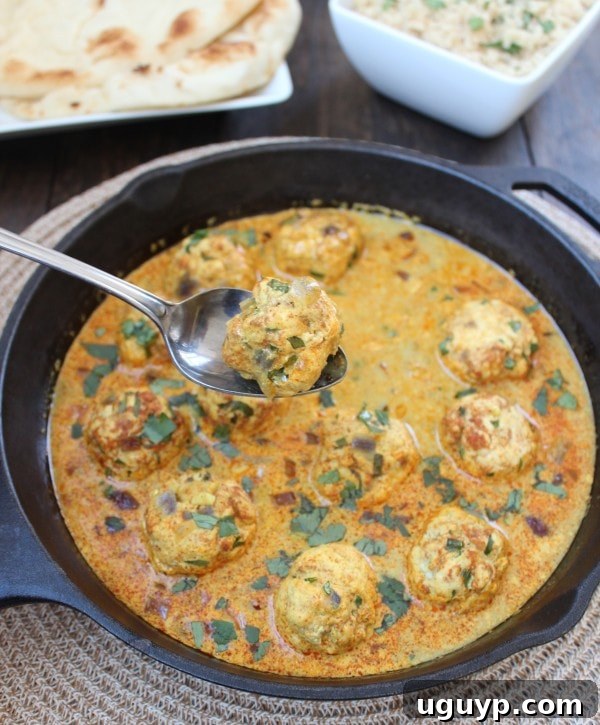Close-up of succulent Gluten-Free Chicken Curry Meatballs in a vibrant sauce, garnished with herbs
