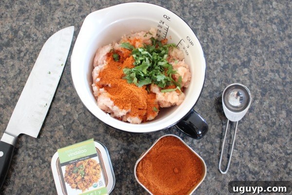 Hands shaping ground chicken mixture into small, uniform meatballs for the curry recipe