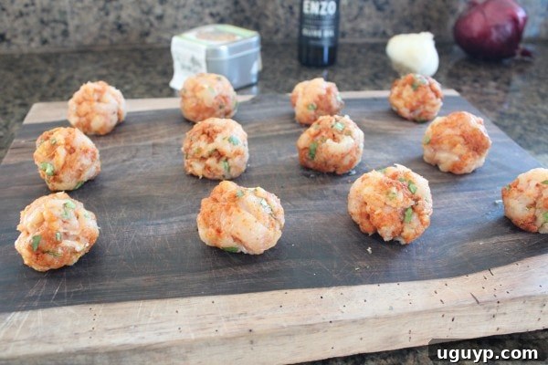 Tray of perfectly shaped chicken meatballs, ready for cooking in the flavorful sauce