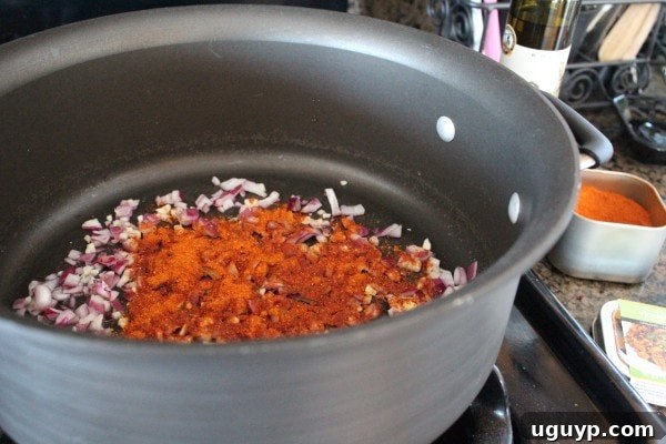 Vindaloo seasoning added to sautéed onions and garlic, enhancing the sauce base