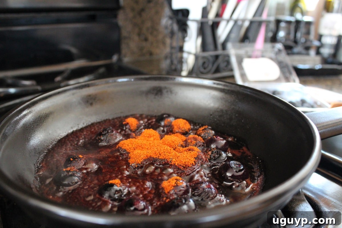 BBQ seasoning being stirred into the blueberry sauce.
