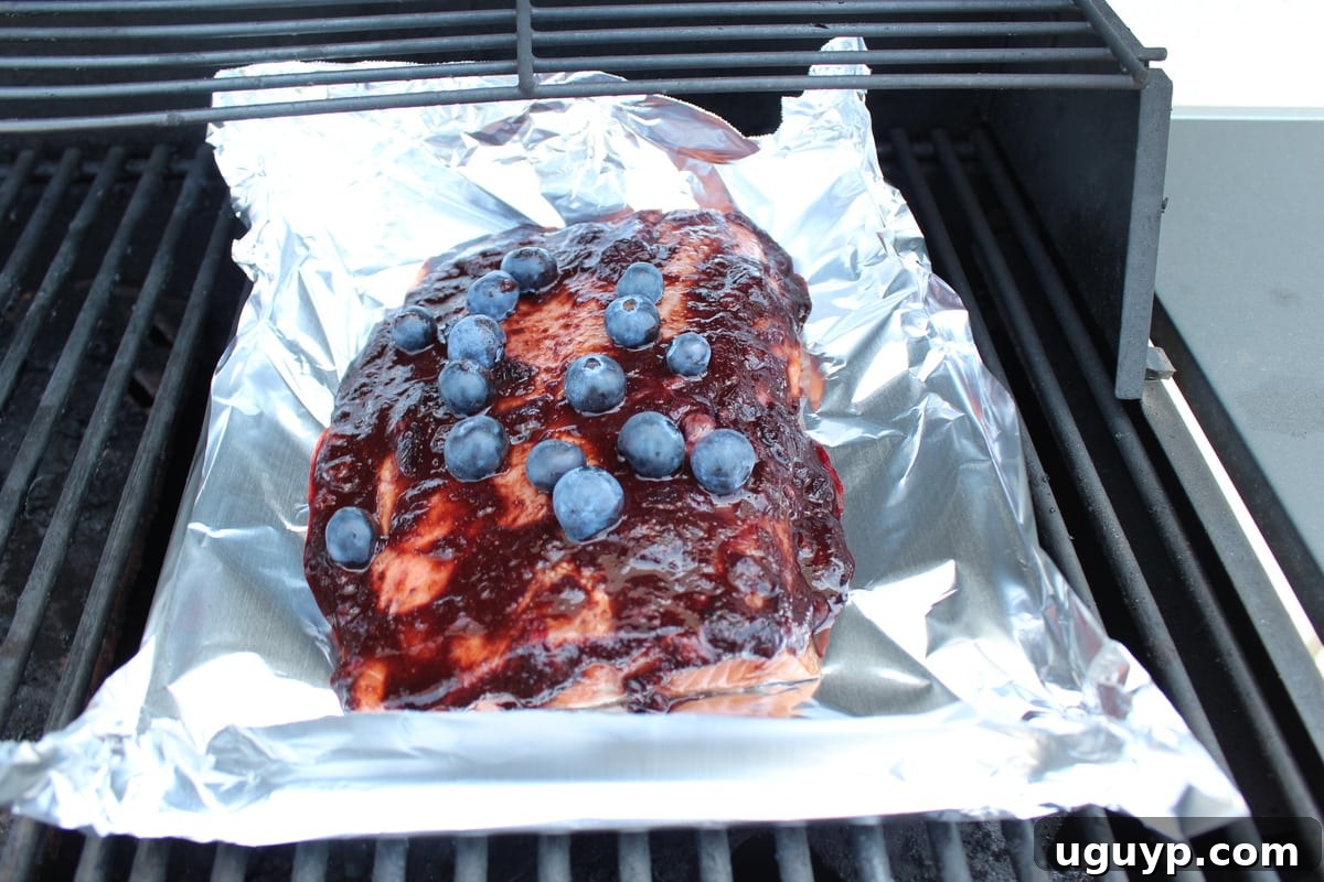 Blueberry BBQ salmon cooking on the grill in a foil basket.