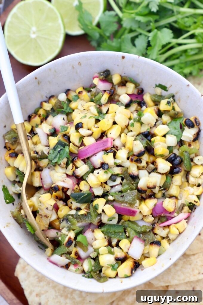 Freshly made corn salsa in a bowl with a serving spoon, ready to be enjoyed.