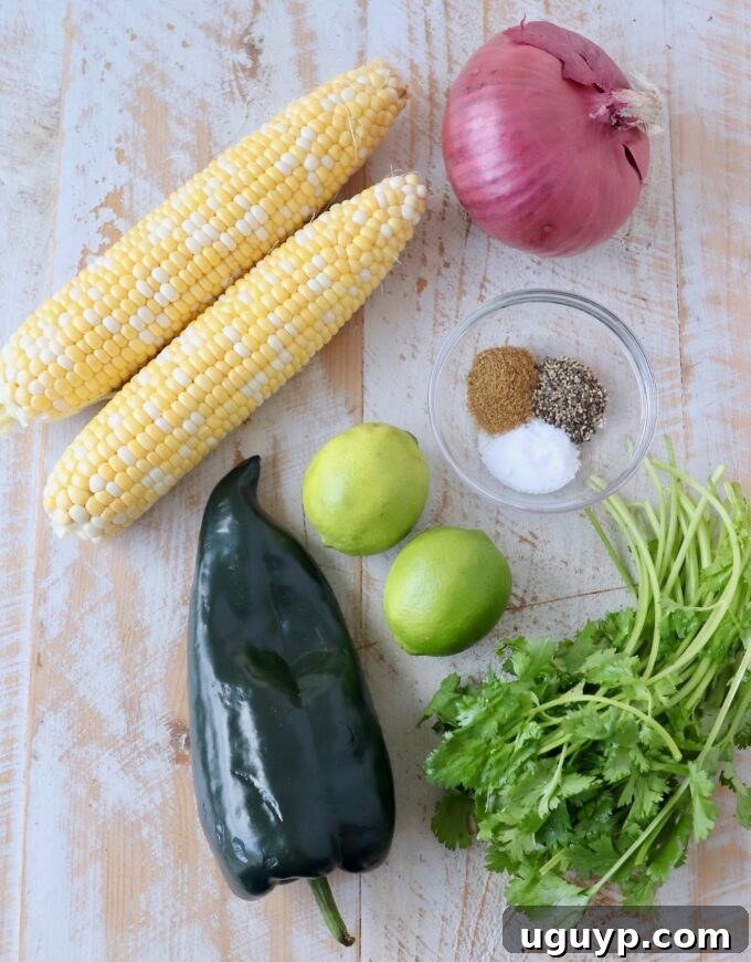A selection of fresh ingredients including corn on the cob, poblano peppers, red onion, and cilantro, ready for preparing corn salsa.