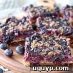 Gluten-free blueberry oat bars, sliced into squares, presented on a wooden cutting board.