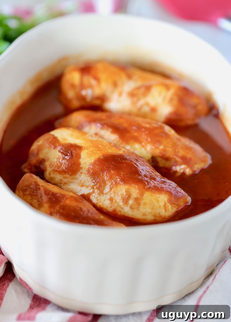 Baked BBQ Buffalo Chicken showcased beautifully in an oval casserole dish, resting on a charming red and white striped towel, highlighting its rich, saucy glaze.