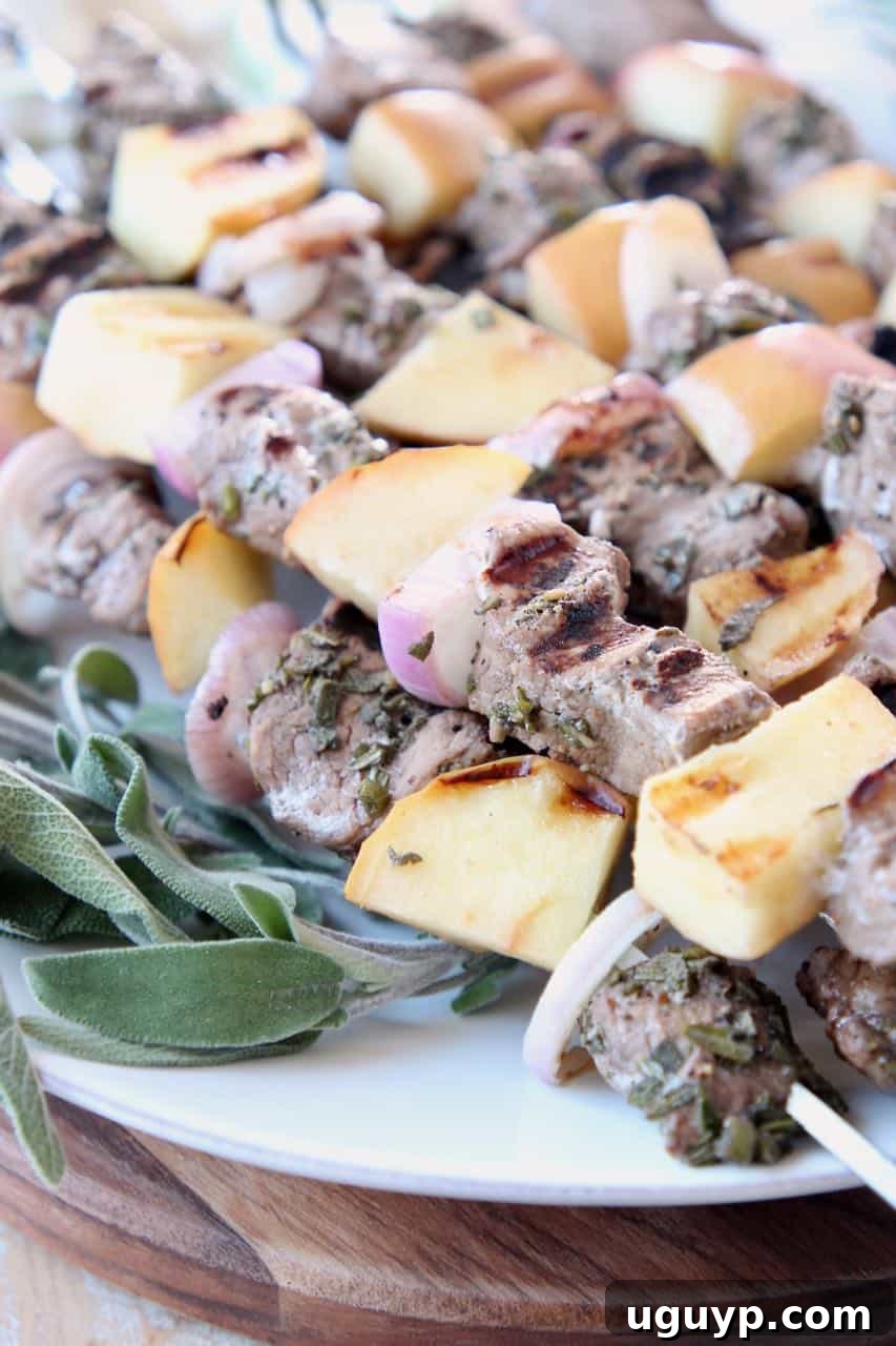 Plated pork and apple skewers garnished with fresh sage leaves, ready to be served