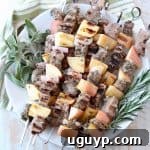 Pork and apple skewers on plate with fresh herbs