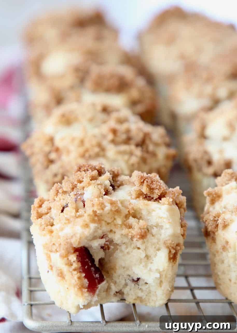 A close-up of a warm Bacon Maple Muffin with a bite taken out, showcasing the moist interior and crispy bacon bits, resting on a wire rack.